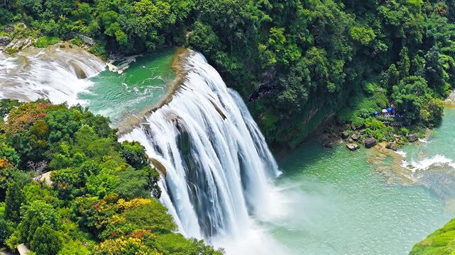 The famous Huangguoshu Waterfall natural landscape in Guizhou, China. Aerial shot of the majestic waterfall cascading into a blue river surrounded by lush forest in summer.