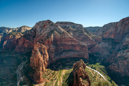 The mountains are covered in red and brown rocks. The sky is clear and blue. The mountains are very tall and steep