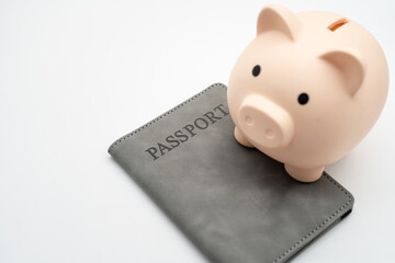 Piggy bank on grey passport holder over white background representing travel savings and budget planning. money saving for future vacations, holiday trips, and global exploration.