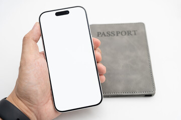 Hand holding smartphone with blank screen and passport on white background for travel app and online booking concept. flight booking, hotel reservations, Digital boarding passes.