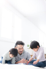 Fototapeta premium 親子でタブレットを使いながら一緒に勉強し遊びながら学ぶ休日の時間 父親と息子(兄弟)の楽しい育児