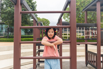 Obraz premium Happy Asian girl playing at playground outdoor in the park at sunset, enjoying active childhood and summer vacation