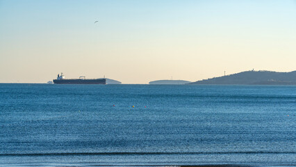 Fototapeta premium Large Cargo Ship in Calm Ocean Near Coast