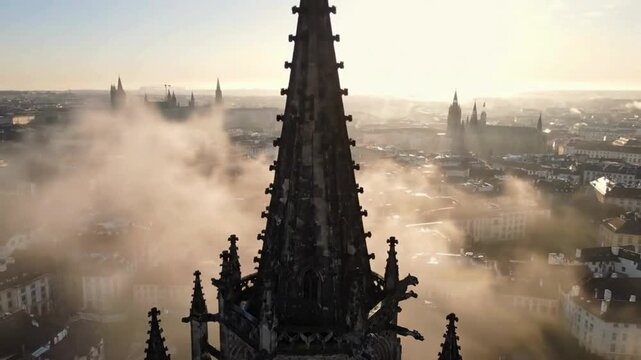 Slow motion aerial dolly shot elevating past frightening stone gargoyles to reveal tall dark gothic spire and christian cross above foggy prague cityscape
