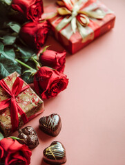 Luxury Valentine still life with red roses, chocolates and gift boxes on pink background