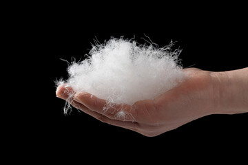 closeup of hand holding down feather isolated on black background