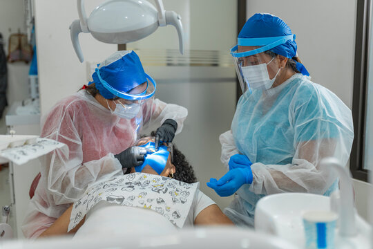 Horizontal shot of a dentist and assistant performing a dental procedure with UV light