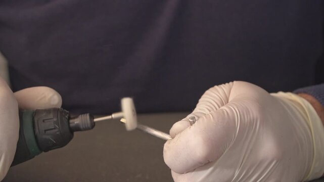 Cordless rotary tool polishing a metal component with felt wheel. rotary tool applies a felt polishing wheel to a dull metal surface. The friction removes oxidation