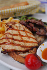 Grilled chicken and beef served with fries and tomato