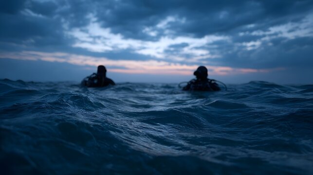 Two scuba divers surface in the choppy ocean waters during twilight under a moody cloudy sky