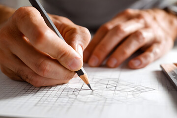 Detail-oriented sketching of architectural plans on paper during daytime at a modern workspace