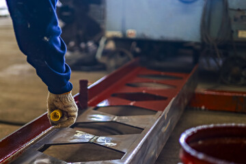 Worker in protective gloves is handling metal beam in industrial setting, showcasing precision and craftsmanship. environment suggests focus on construction or manufacturing processes