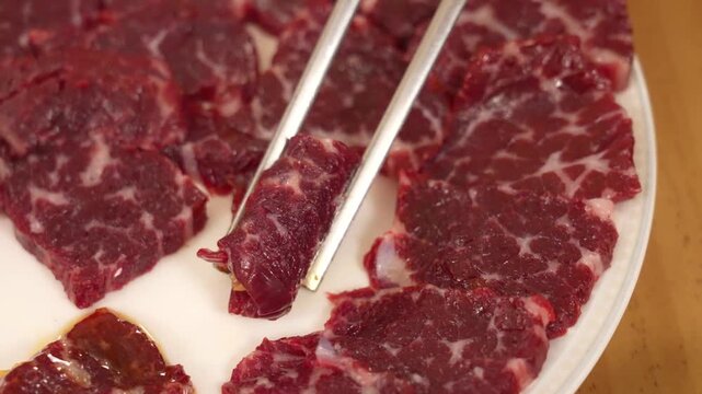 Picking up seasoned Korean beef chunk with chopsticks
