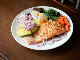 healthy dish with grilled salmon fillet, boiled egg, blanched spinach and carrot, fresh avocado and shallot