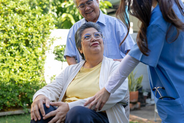 Fototapeta premium Asian senior woman in wheelchair smiling and interacting with nurse , elderly man outdoors, concept of elderly care, support, rehabilitation, assisted living and nursing home services.