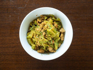 top view stir fried bitter gourd and minced pork with yellow curry paste, topped with kaffir lime leaf chiffonade