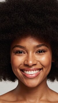 Radiant young woman with large afro, wide smile, and glowing skin