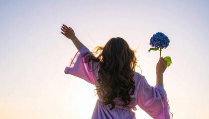 Woman holding blue hydrangea flower towards sunny sky in nature
