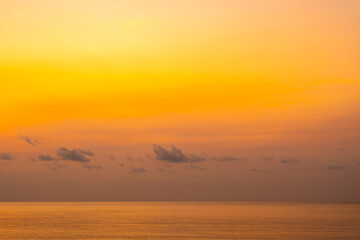 Nature sky breathtaking golden sunset over a calm ocean, with the entire sky and water bathed in brilliant shades of yellow and orange. Streaky clouds enhance the dramatic display of light	