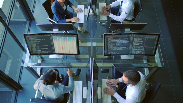 glasswalled office developers pairprogramming while monitoring system dashboards from overhead view, dual monitors display code and analytics, team discussing deployment and testing