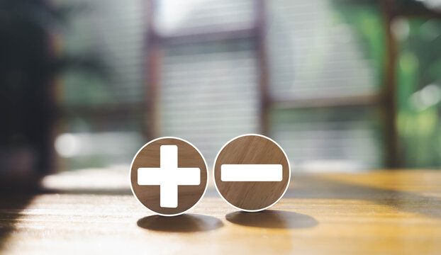Minimal plus and minus symbols on wooden circles represent decision making, choice comparison, advantages and disadvantages, financial balance, business strategy, and positive or negative concepts.