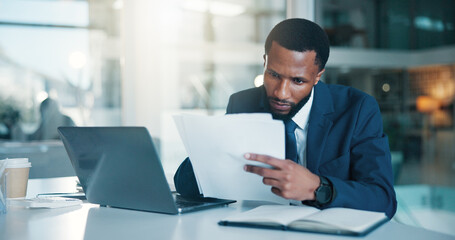 Obraz premium Investor, laptop and black man with documents, reading and checklist for company audit. African person, trading strategy and financial advisor in office, pc and research for stock market and planning