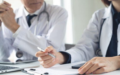 Two asian doctors discuss diagnosis, analyzing data on laptop in hospital office. Male and female medical professionals have a patient case conference, using laptop at doctor's office, close up