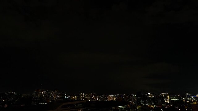A massive storm slams into Brisbane city, creating a dramatic display of intense lightning that illuminates the dark, ominous sky, as extreme weather sweeps across Southeast Queensland.