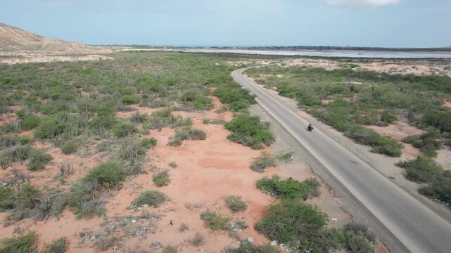 Aerial view tracking motorcycle on desert road Araya Peninsula