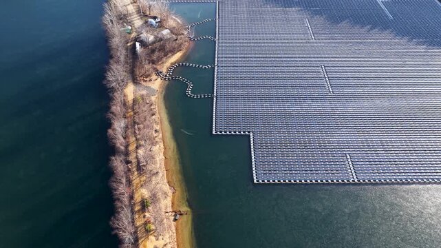 Aerial view of large floating solar panel array with its shore attachment