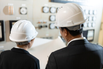 Male and female engineers collaborate in a high-tech power plant control room, analyzing blueprints to monitor energy flow, reduce risks, and ensure continuous performance of critical systems.