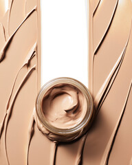 Open glass jar of creamy beige foundation surrounded by thick cosmetic texture swatches