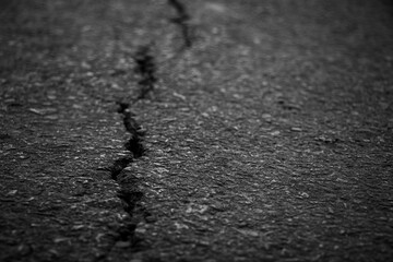 Close-up view of cracked road surface revealing detailed asphalt damage and texture.