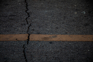 Close-up asphalt road surface showing natural cracks and aging pavement details.