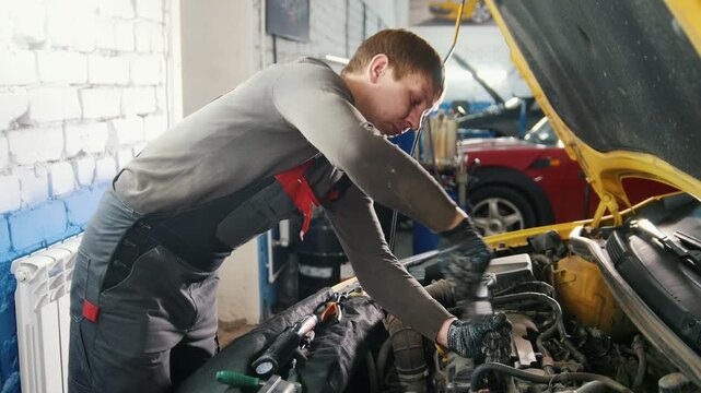 Car auto service - mechanic unscrews detail of car