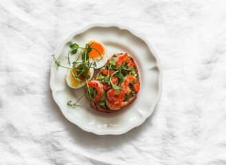 Delicious breakfast, brunch, tapas, snack - boiled egg and avocado, shrimp sandwich on a light background, top view
