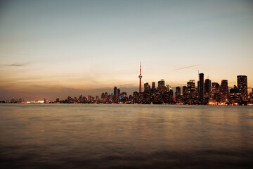 Naklejka premium Toronto skyline at dusk with illuminated city lights reflecting on the water, vibrant urban night view. g.