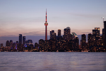 Naklejka premium Toronto skyline at dusk with illuminated city lights reflecting on the water, vibrant urban night view. g.