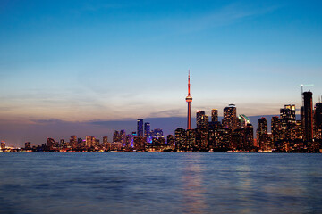 Naklejka premium Toronto skyline at dusk with illuminated city lights reflecting on the water, vibrant urban night view. g.
