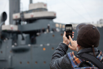 Naklejka premium tourist takes smartphone photo of historic revolutionary warship