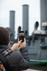 Naklejka premium tourist takes smartphone photo of historic revolutionary warship