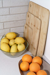 Fresh lemons and oranges arranged with wooden cutting boards on a kitchen counter, preparing for a healthy meal