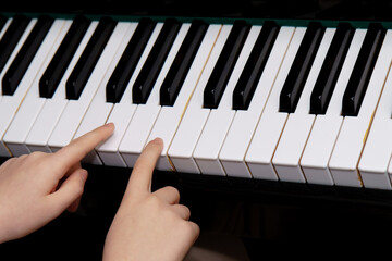 Child's hands pressing white keys on a piano keyboard, learning to play music, symbolizing practice and early musical education