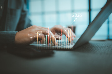 Close-up of hands typing on laptop with digital financial growth chart and future years projection