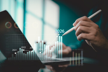 Business person analyzing financial growth data on laptop with digital bar graph and futuristic projections for 2026