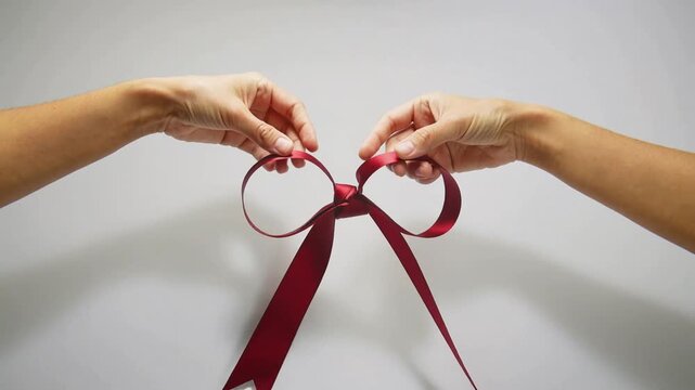 Hands Creating Red Ribbon Bow Gift.