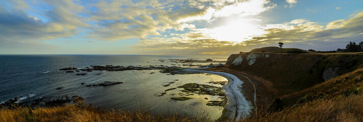 Panorama of rugged coastal cliffs and ocean at sunset