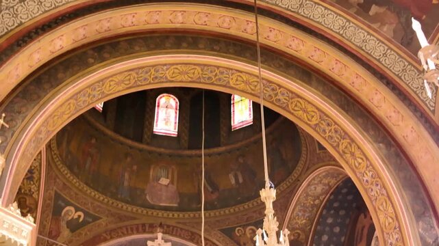 Frescoed walls and hanging chandeliers inside the Dormition of the Mother of God Church in Brașov, Romania.