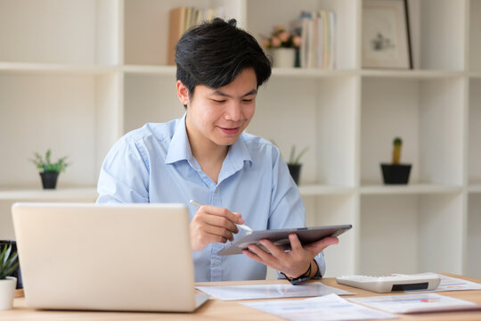 Young accountant working with digital tablet and laptop at desk, reviewing financial documents. Concept of accounting and financial analysis. - Powered by Adobe
