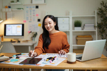 UX UI designer sketching mobile app wireframes while testing interface ideas on tablet. Concept of user centered design and digital product development.